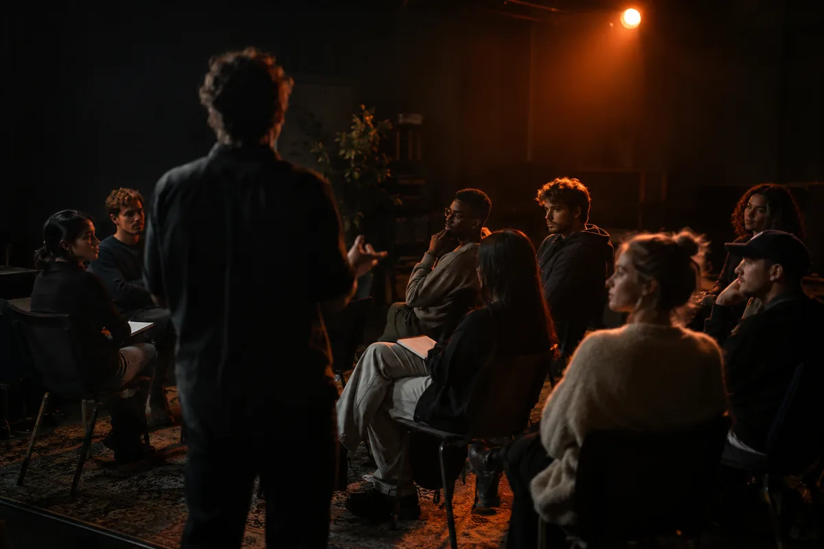 Group of young people listening to a speaker in a dark training room